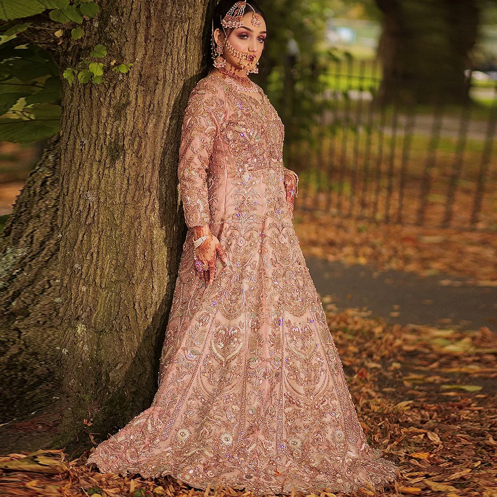 A close-up of a bride walking or turning, the sheer cape dupatta flowing mid-motion with crystal or pearl embellishments.
