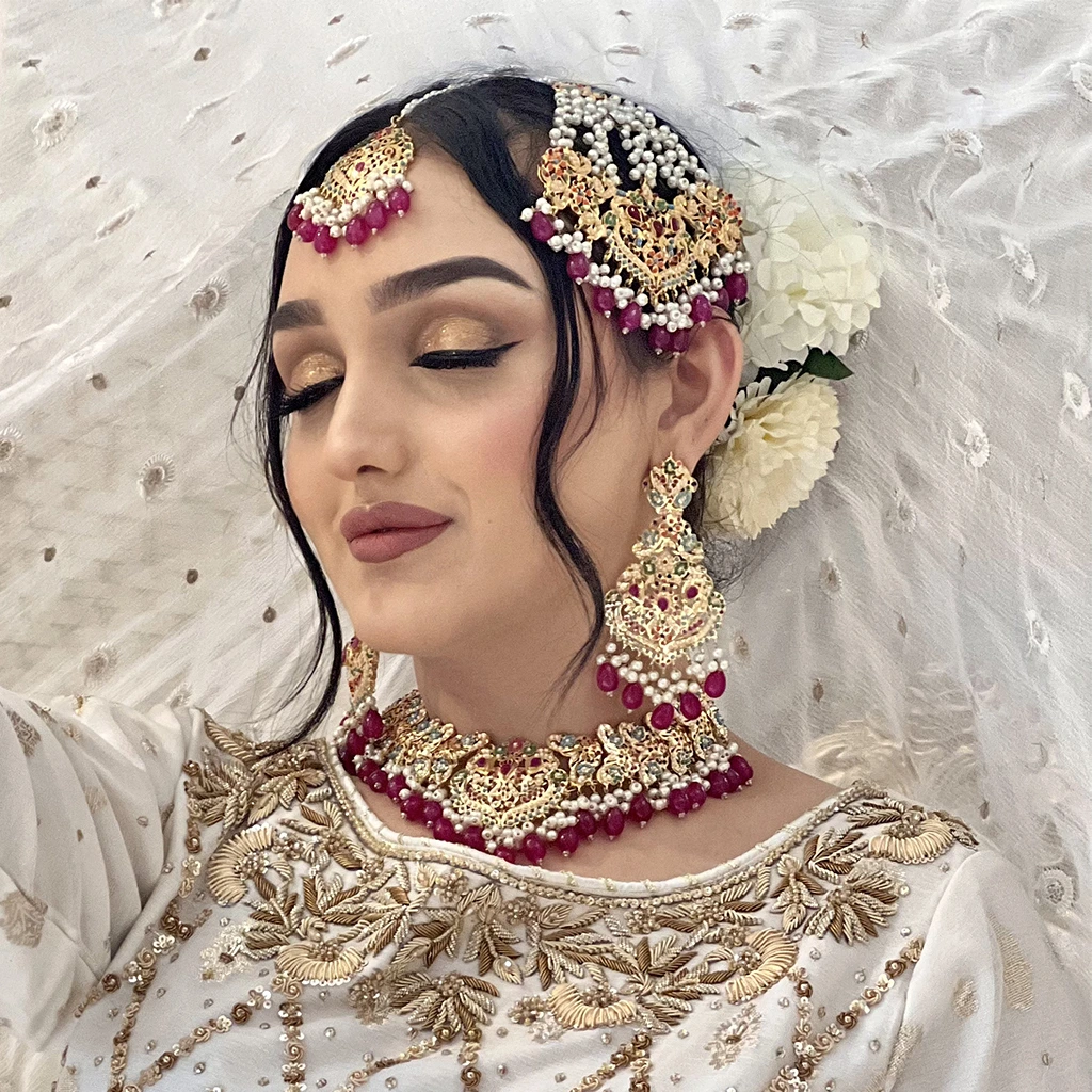 : Flat lay of accessories – jhumkas, matha patti, and pearl drop earrings.