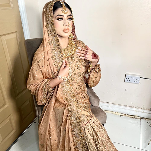 • Bride with faux fur-trimmed shawl, metallic brocade lehenga catching candlelight.
